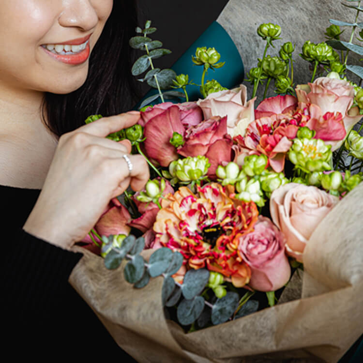 花束を笑顔で眺める女性の写真